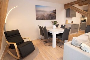 Um espaço de estar moderno com uma mesa de jantar, cadeiras, um sofá, um quadro e uma área de cozinha.