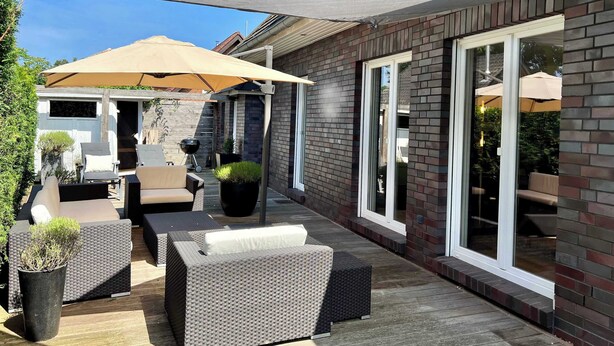 A patio with outdoor furniture, a barbecue grill, and a large umbrella. - Exklusives Ferienhaus Celeste nahe Warnemünde – Luxus & Entspannung für bis zu 7 Personen (Rostock)
