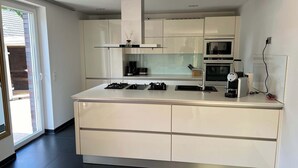 A modern kitchen with a central island, built-in appliances, and a large window. - Exklusives Ferienhaus Celeste nahe Warnemünde – Luxus & Entspannung für bis zu 7 Personen (Rostock)