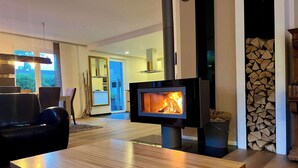 A modern living room with a wood-burning stove, a dining area, and a view of the outdoors. - Exklusives Ferienhaus Celeste nahe Warnemünde – Luxus & Entspannung für bis zu 7 Personen (Rostock)
