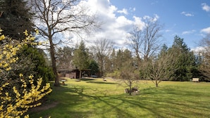 A grassy outdoor area with trees, a wooden structure, and a bench. - Ferienhaus Neuland 5 - Entspannung in Seenähe (Lychen)