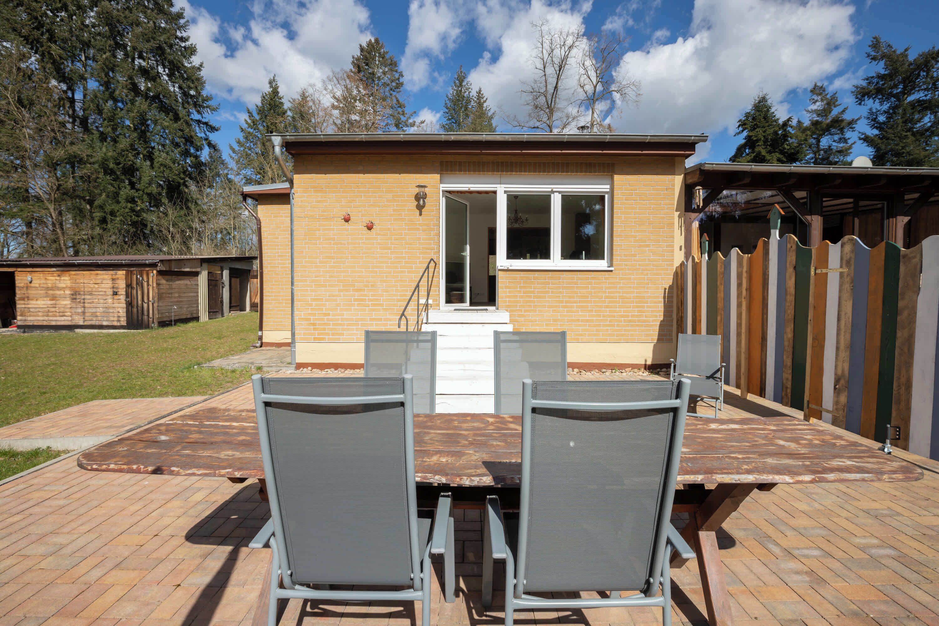 A patio with a table and chairs, a brick building, and a wooden fence.
