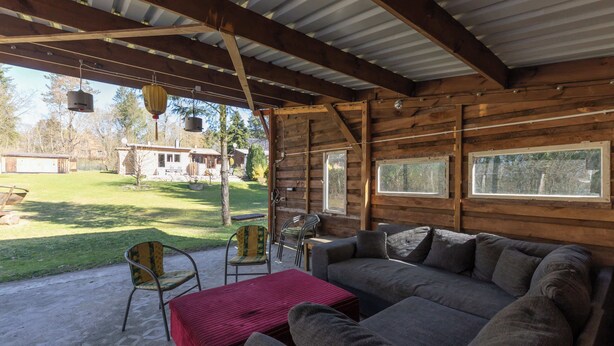 A covered outdoor seating area with a sofa, chairs, and a table. - Ferienhaus Neuland 5 - Entspannung in Seenähe (Lychen)