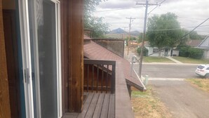 A wooden deck with a glass door leading to a room. A metal railing borders the deck.