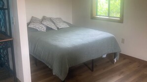 A bedroom with a bed, a window, and a ceiling light fixture.