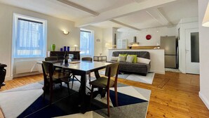 Una sala de estar moderna con comedor, piso de madera y ventanas grandes.