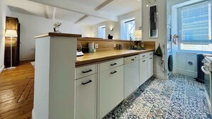 Una cocina moderna con encimera de madera, armarios blancos y baldosas de suelo estampadas.