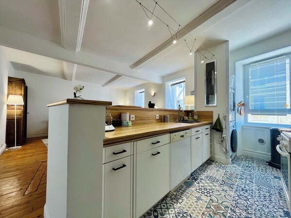 Une cuisine moderne avec un plan de travail en bois, des armoires blanches et des carreaux de sol à motifs.