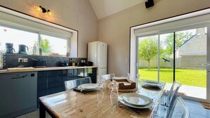 Una cocina moderna con comedor, ventanas amplias y vista al jardín trasero.