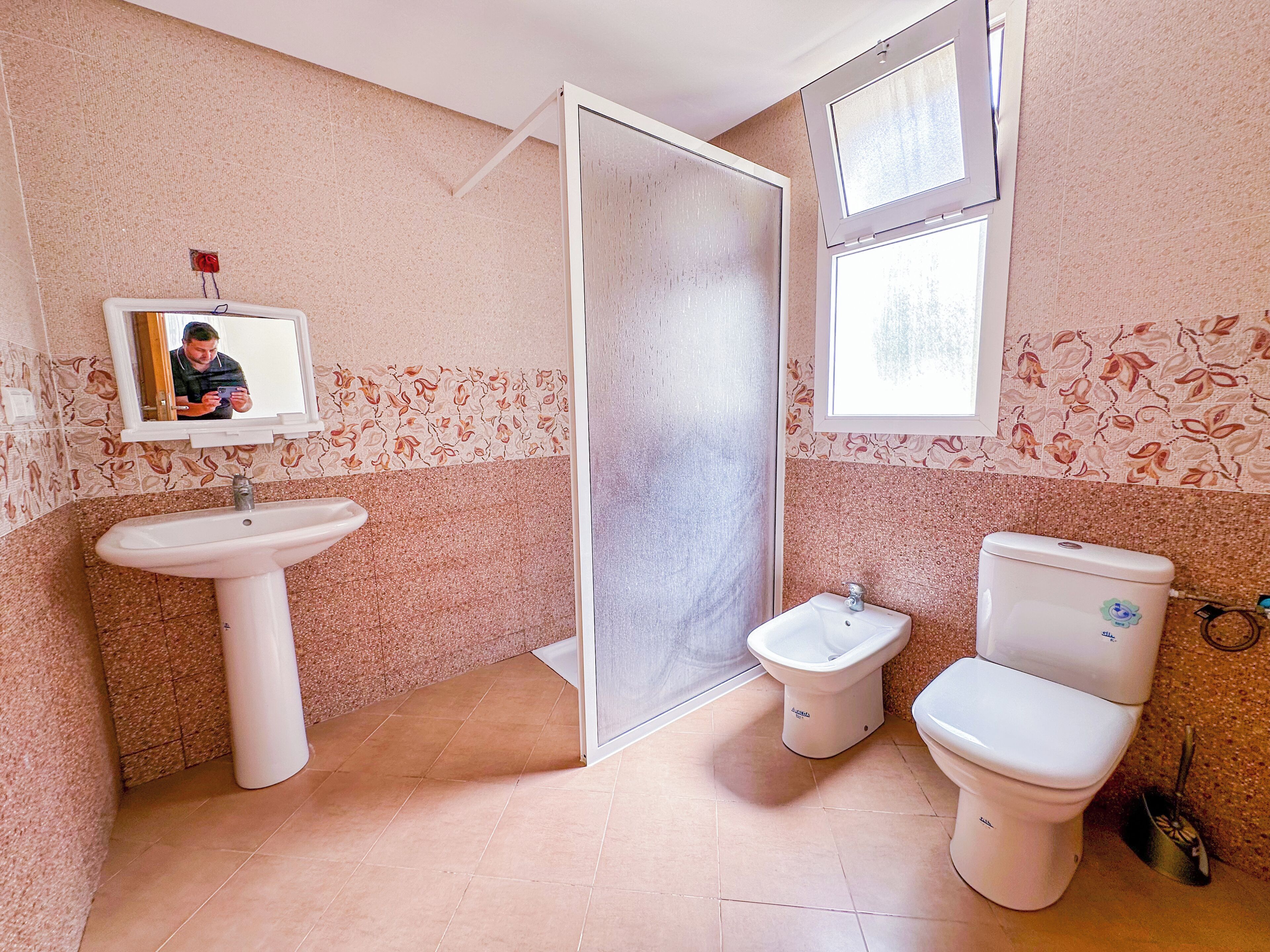 A bathroom with a sink, toilet, bidet, and a shower area.