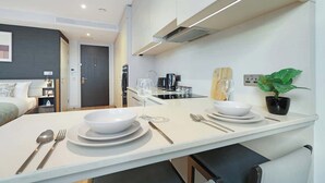Une cuisine moderne avec un coin repas, équipée d’une cuisinière, d’un évier et d’une plante en pot.