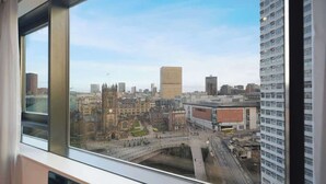 Une vue sur une ville à travers une fenêtre, avec un pont, des immeubles et un ciel dégagé.