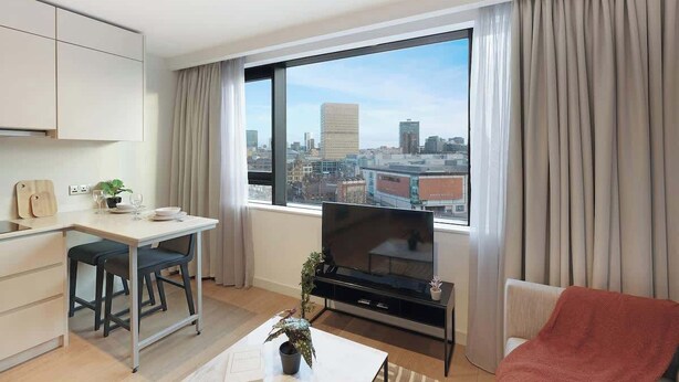 Un appartement moderne doté d’un coin repas, d’une télévision et offrant une vue sur la ville.