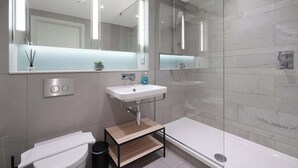 Une salle de bain moderne équipée de toilettes, d’un lavabo et d’une douche.