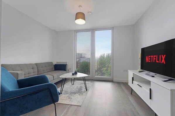 Ein modernes Wohnzimmer mit einer Couch, einem Couchtisch, einem Fernseher und einer Schiebetür aus Glas.