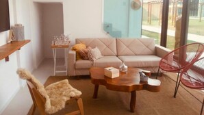 A modern living room with a sofa, a wooden coffee table, a red chair, and a glass door leading to an outdoor area. - Casa milagres Morada do toque (São Miguel dos Milagres)