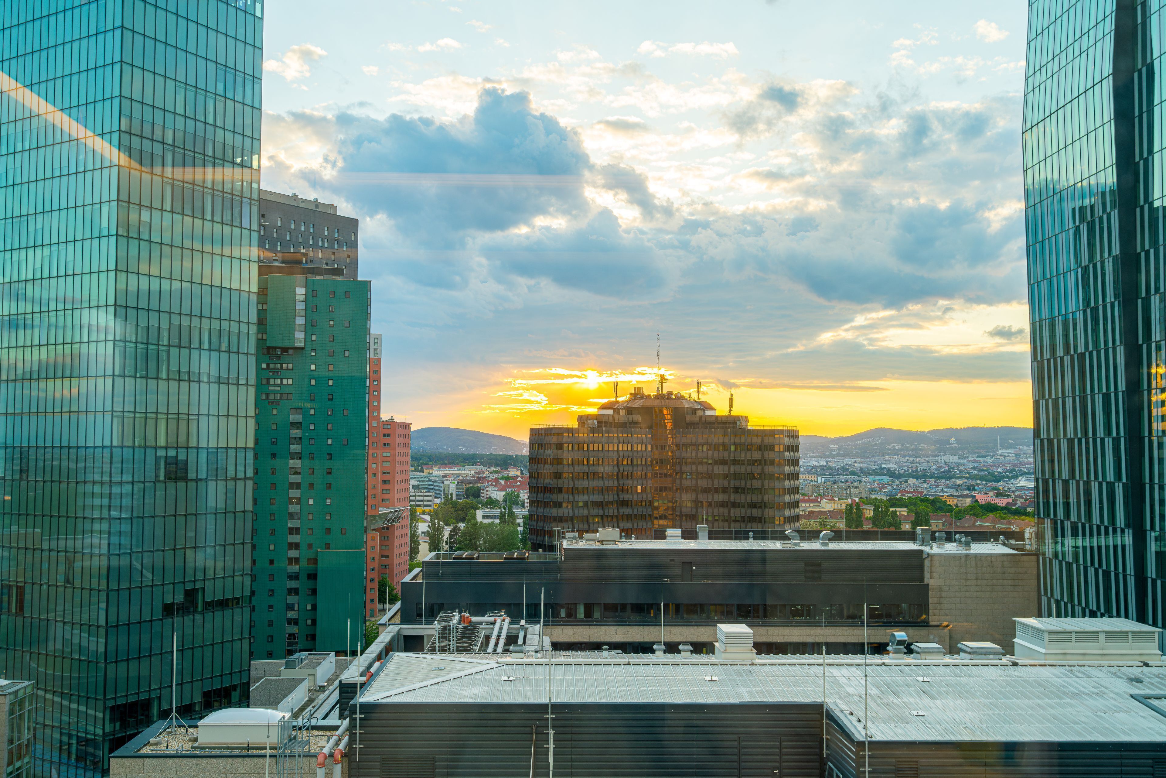 Paesaggio urbano con edifici moderni e un tramonto sullo sfondo.