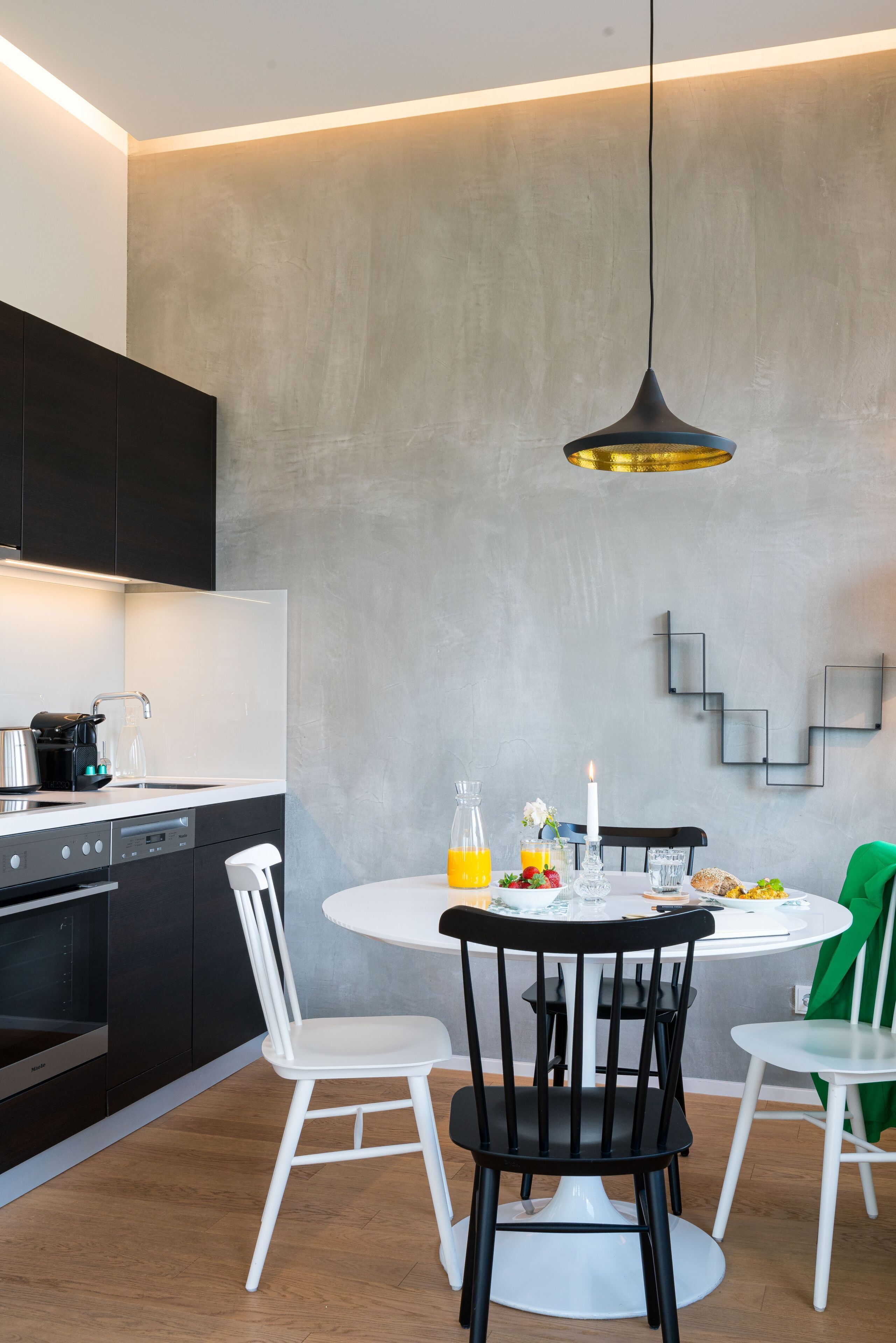 Een moderne keuken met een eethoek, met een ronde tafel, stoelen en een hanglamp.