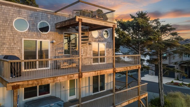 A multi-story house with a wooden deck, large windows, and a balcony.