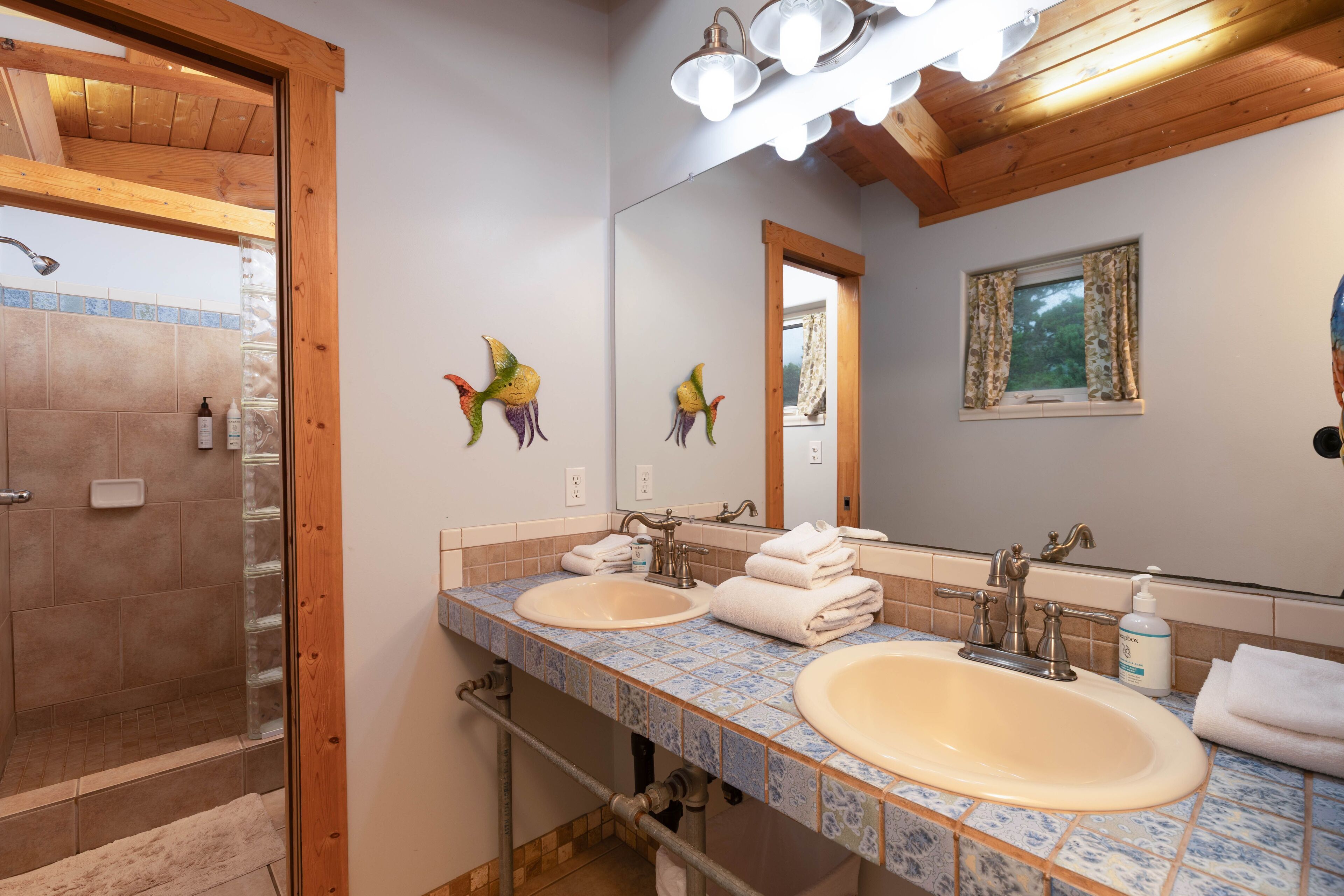 A bathroom with two sinks, a shower, and a wooden ceiling.