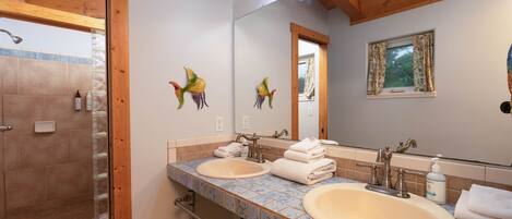 A bathroom with two sinks, a shower, and a wooden ceiling.