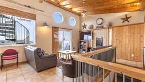 A cozy interior with a spiral staircase, wooden ceiling, and a view of the outdoors.