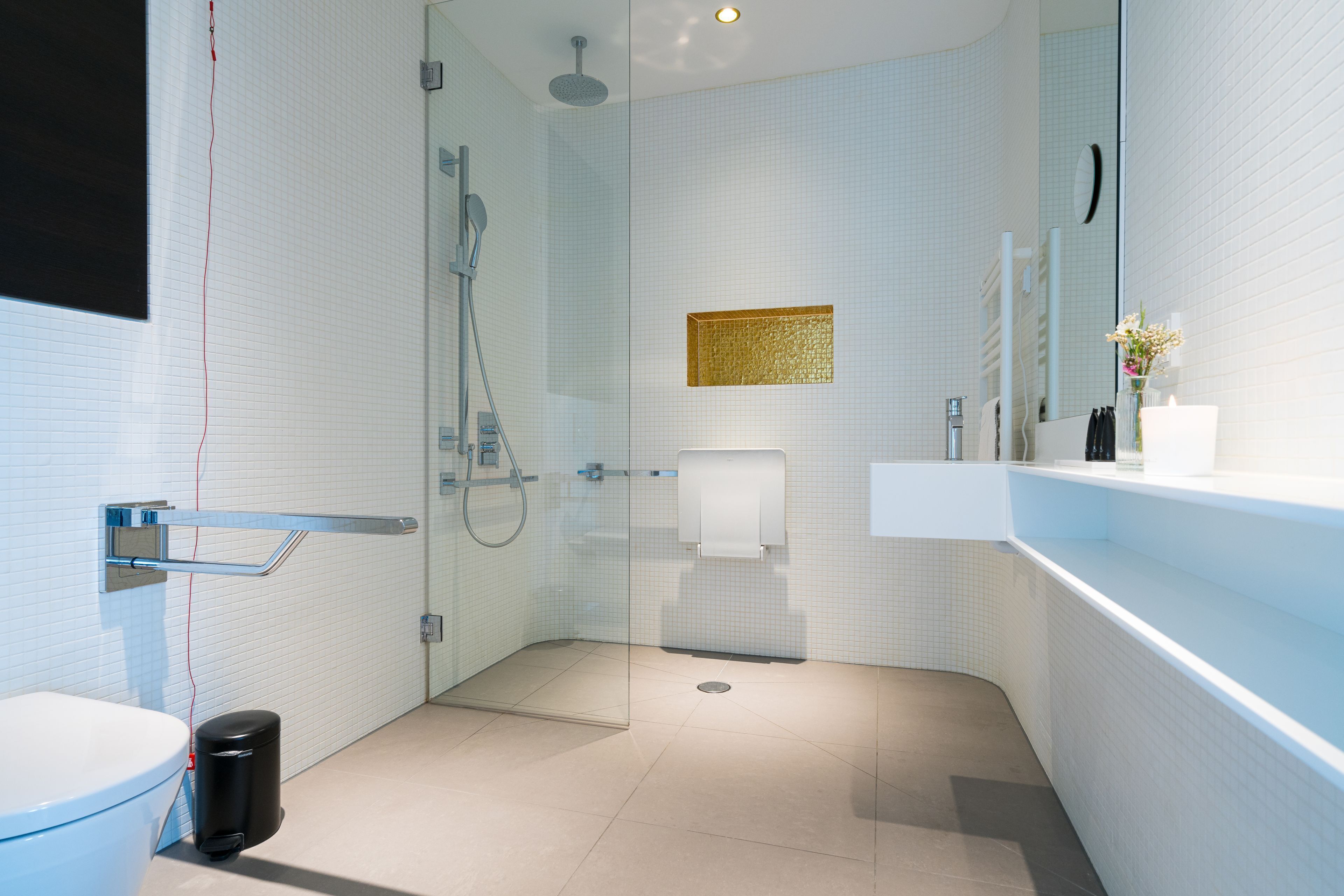 Une salle de bain moderne avec une douche à parois de verre, des toilettes blanches et un lavabo avec un miroir au-dessus.