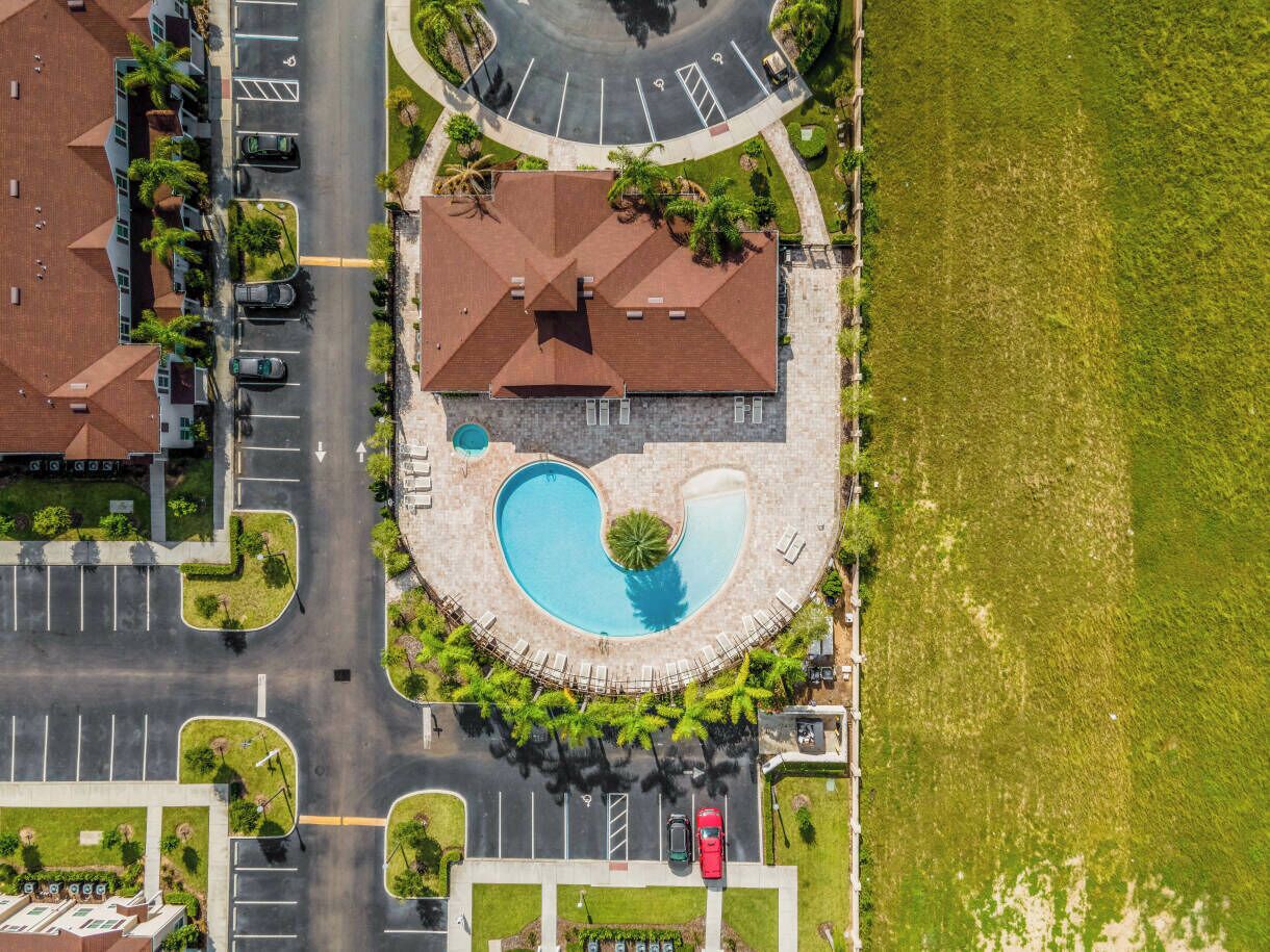 Vue aérienne d’un quartier résidentiel avec une piscine, des parkings et des maisons.
