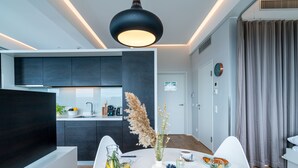 A modern kitchen with dark cabinets, a white countertop, and a dining area with a white table set for breakfast. - Vienna Residence, Philips Haus - Euro Plaza #6554 (Vienna)
