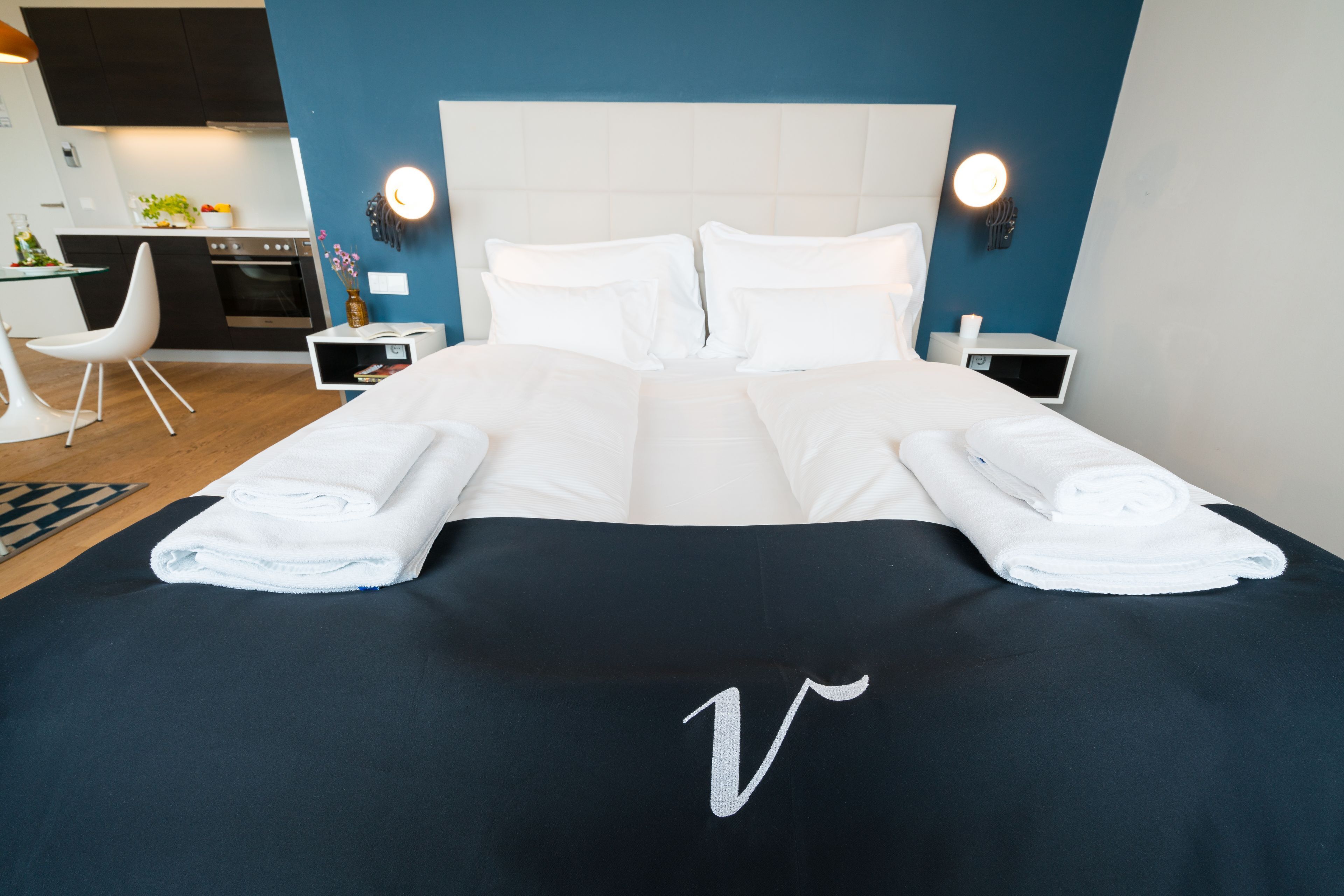 Une chambre d’hôtel avec un grand lit, deux tables de chevet, une petite table, un bureau et une chaise.