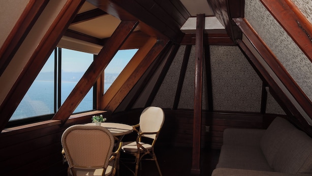 A cozy attic room with a wooden ceiling, a round table, two wicker chairs, and a sofa. - Hotel vista velero (Vina del Mar)