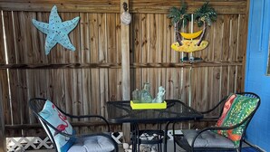 A patio with a wooden fence, a starfish decoration, a hammock, and a table with chairs.