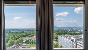 A window with curtains, offering a view of a cityscape with buildings and greenery. - Vienna Residence, Philips Haus - Euro Plaza #6605 (Vienna)