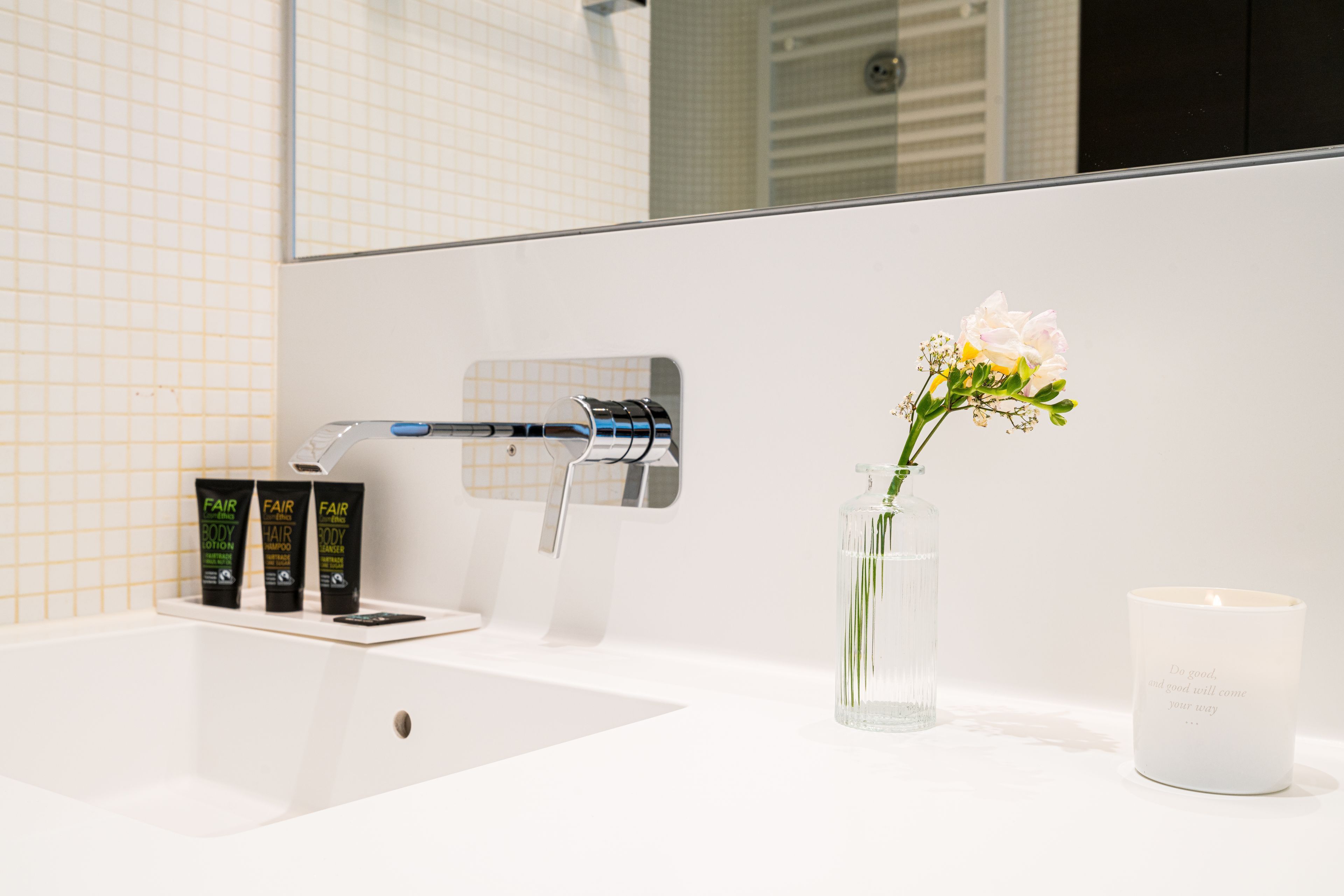 A bathroom with a white sink, a mirror, and a bottle of lotion.