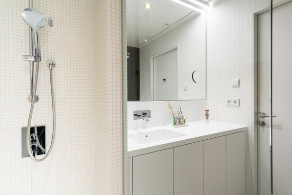 Une salle de bain moderne avec une douche, un lavabo et un miroir.