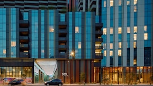 A modern building with a prominent 'SOL' sign, large windows, and a covered entrance. - Sentral Sol Modern (Phoenix)