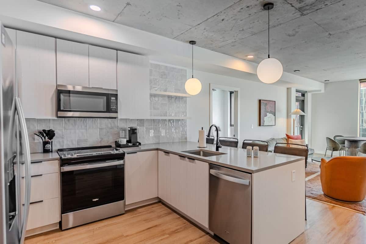A modern kitchen with stainless steel appliances, a central island, and pendant lighting.