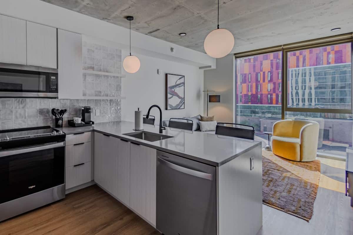 A modern kitchen with stainless steel appliances, a central island, and a large window with a city view.