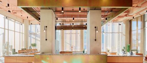 A spacious lobby with a reception desk, large windows, and modern lighting fixtures.