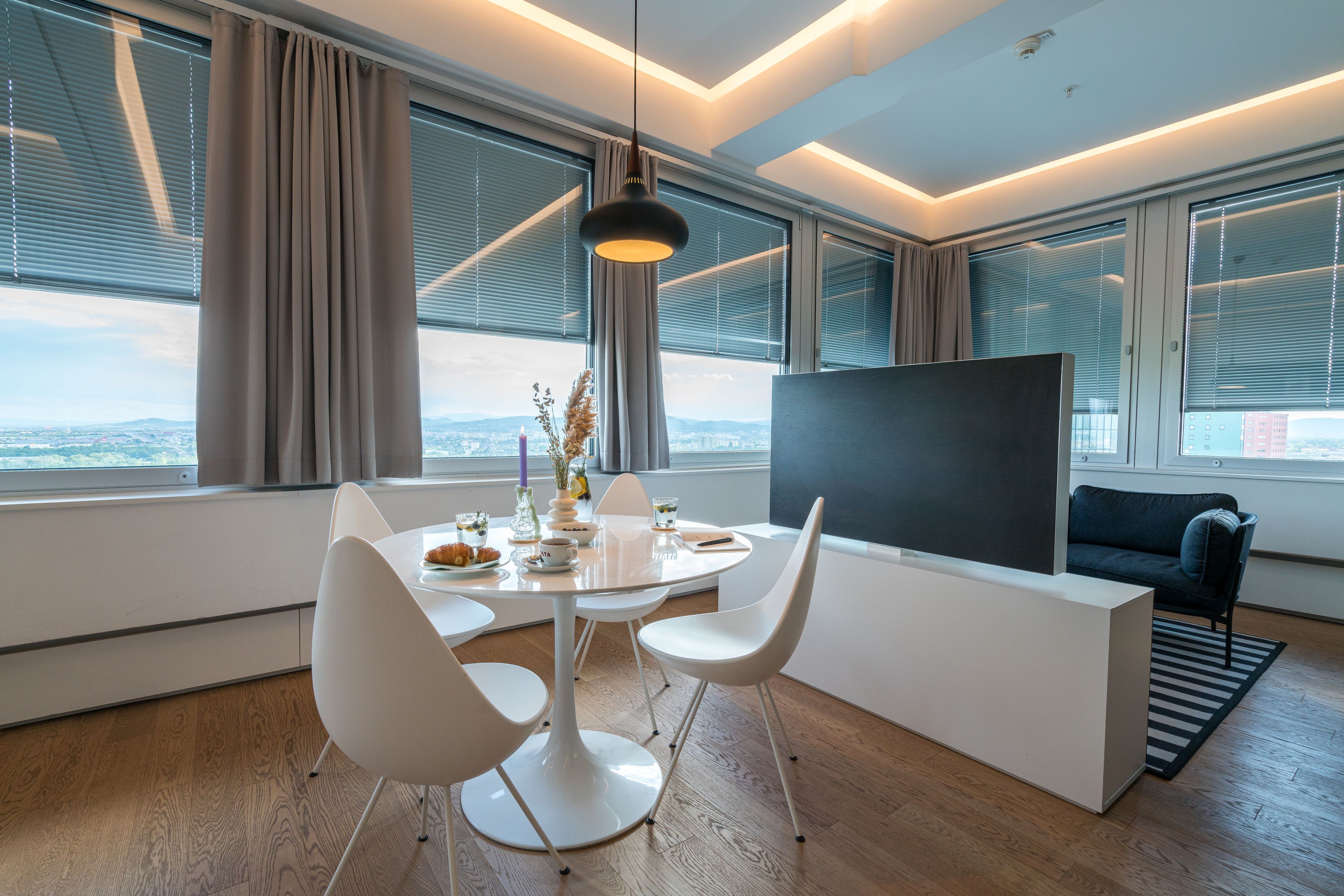 Un salon moderne comprenant un coin repas, de grandes fenêtres, un téléviseur à écran plat et un canapé.