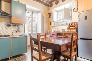 A kitchen with teal cabinets, a wooden dining table, and a Samsung refrigerator. - Apartment 'Fatima' with Private Garden and Wi-Fi (Lucca)