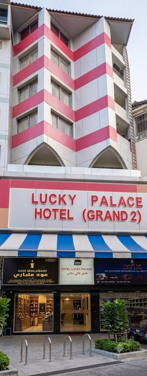 A hotel named Lucky Palace with a distinctive striped facade and a sign indicating it is Grand 2. - hotel lucky palace  (Bangkok)