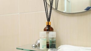 A bathroom with a glass shelf holding a bottle of liquid soap, a white towel, and a round soap dish. - hotel lucky palace  (Bangkok)