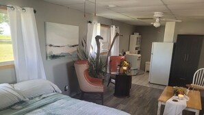 Una habitación con cama, una mesa de comedor con sillas, una pequeña cocina y una planta en maceta.