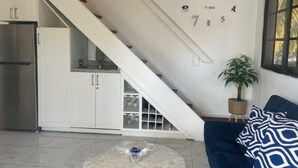 Eine moderne Küche mit weißen Schränken, einem Edelstahl-Kühlschrank und einer Treppe, die in einen Essbereich führt.