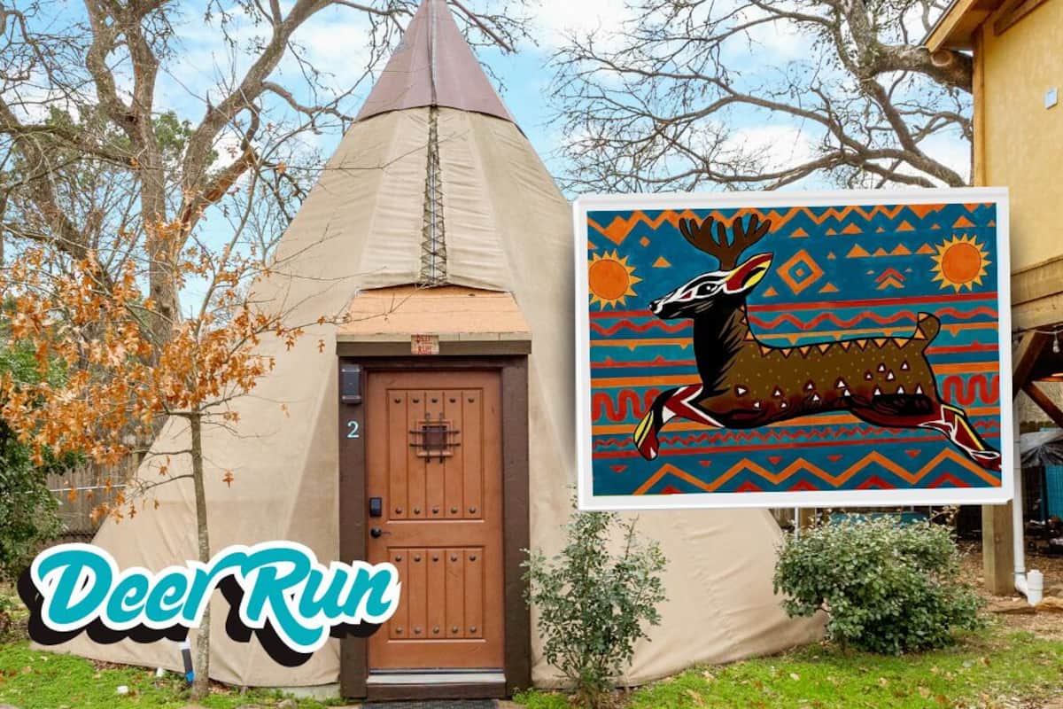 A tent with a conical roof, a wooden door, and a colorful mural of a moose.