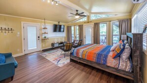 A spacious bedroom with a large bed, a ceiling fan, and a TV mounted on the wall. - Tipis on the Guadalupe (New Braunfels)