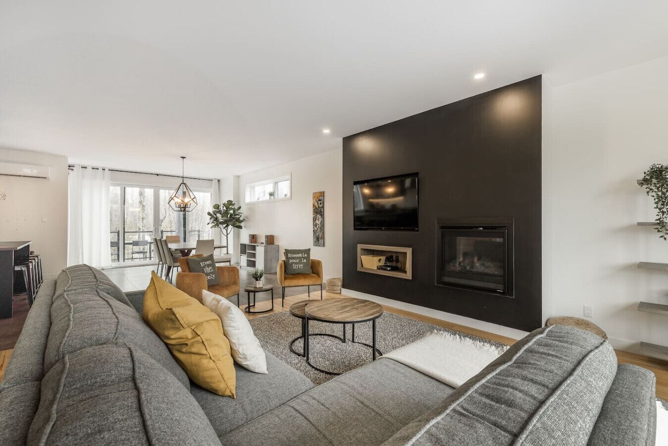 A modern living room with a grey sofa, a round coffee table, and a fireplace.