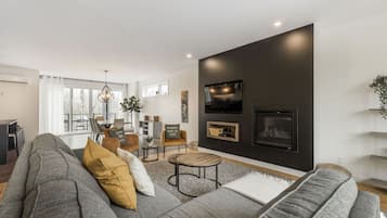 A modern living room with a grey sofa, a round coffee table, and a fireplace.
