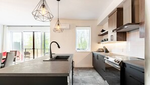 Una cucina moderna con isola centrale, elettrodomestici in acciaio inossidabile e luci a sospensione.